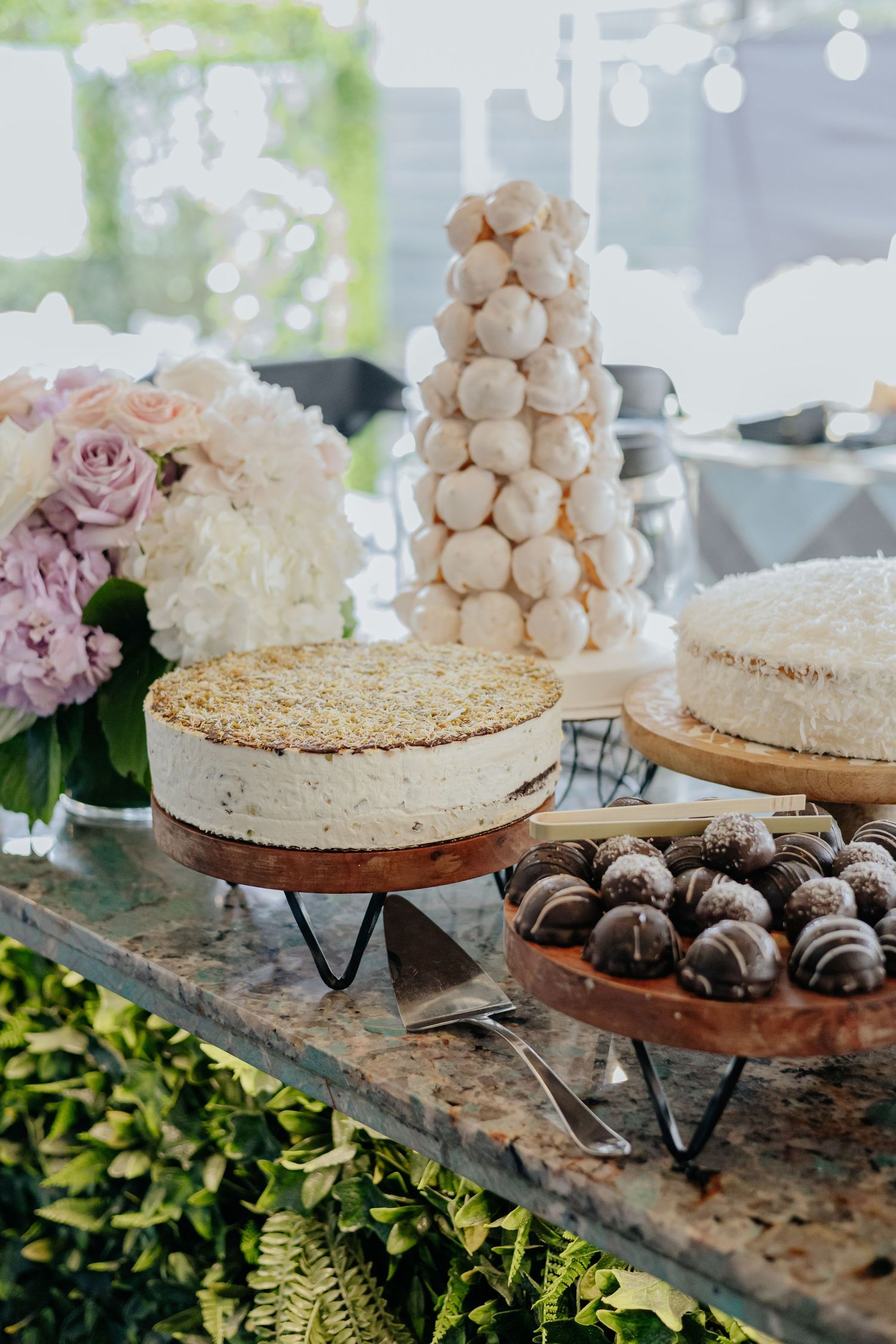 Elegant dessert table with layered cakes, cake pops, and chocolate truffles at a bridal shower.