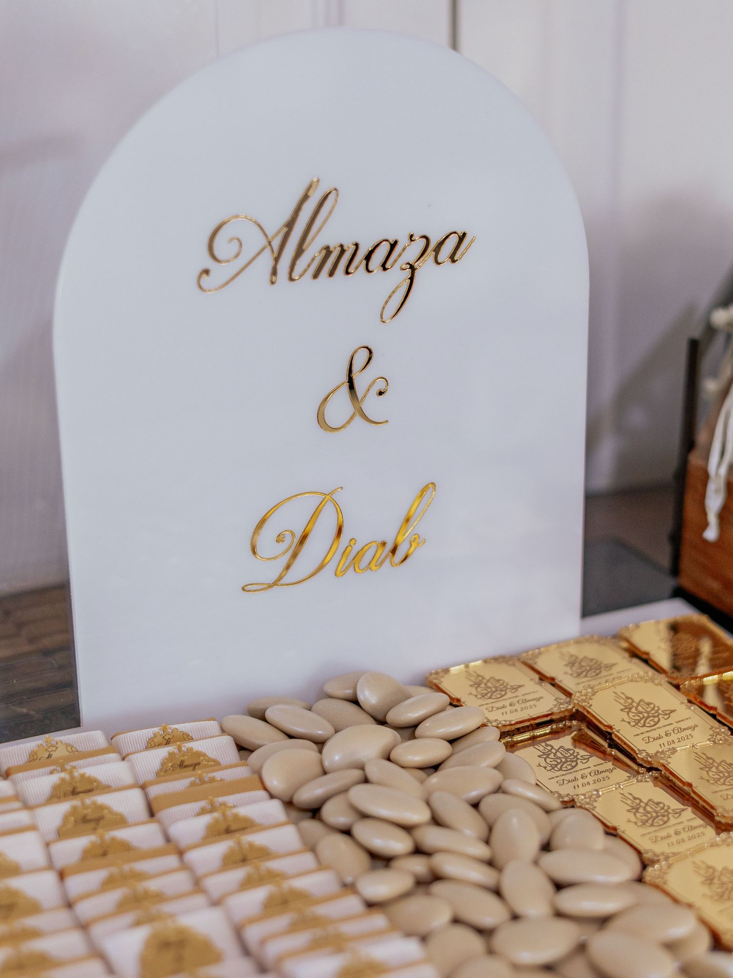 Wedding candy table sign reading Almaza and Diab in gold script with Jordan almonds and gold wrapped sweets.