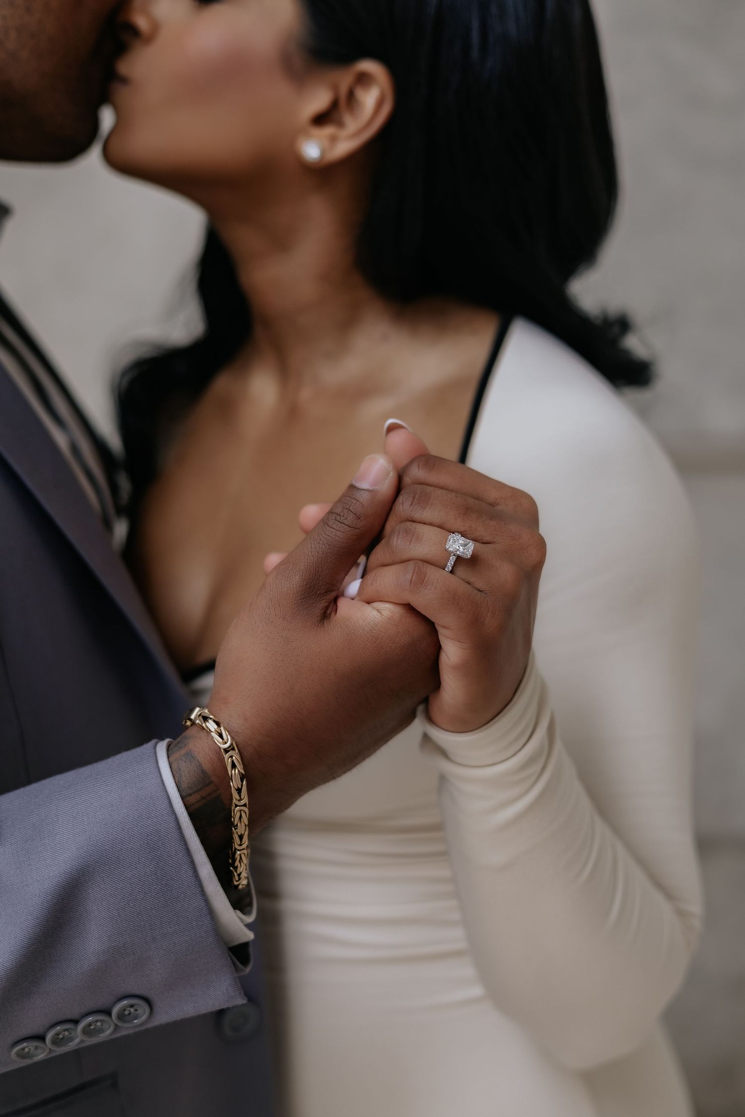 Close-up of engaged couple holding hands, showcasing a stunning diamond engagement ring.