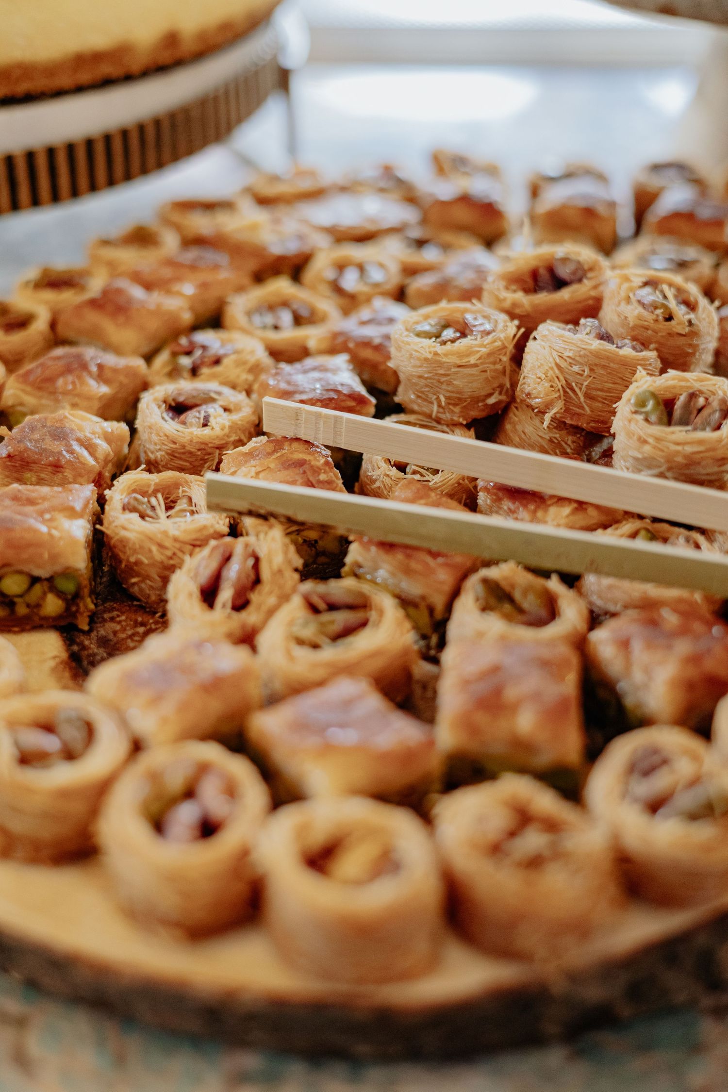 Tray of golden baklava rolls with nuts served on a wooden board at a bridal shower.
