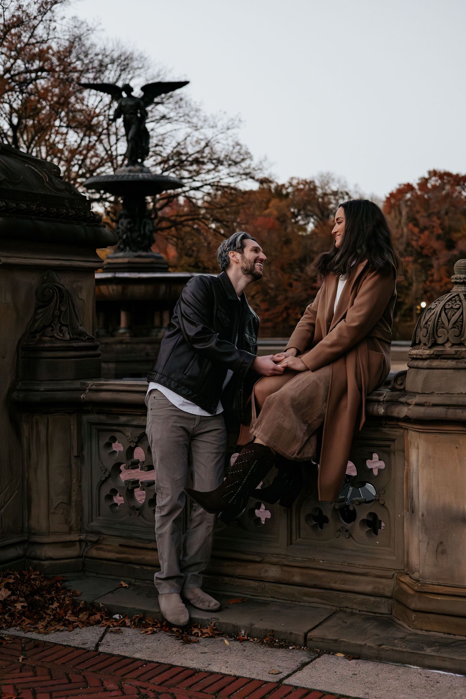 Couple holding hands near Bethesda Fountain in Central Park during autumn foliage season.