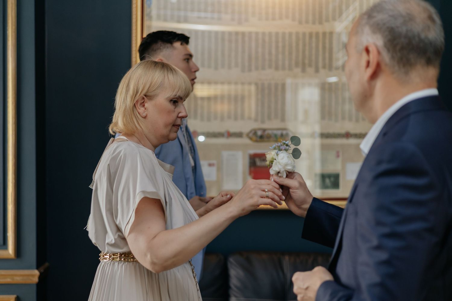 Elegant woman in beige dress receiving drink at sophisticated wedding reception gathering.