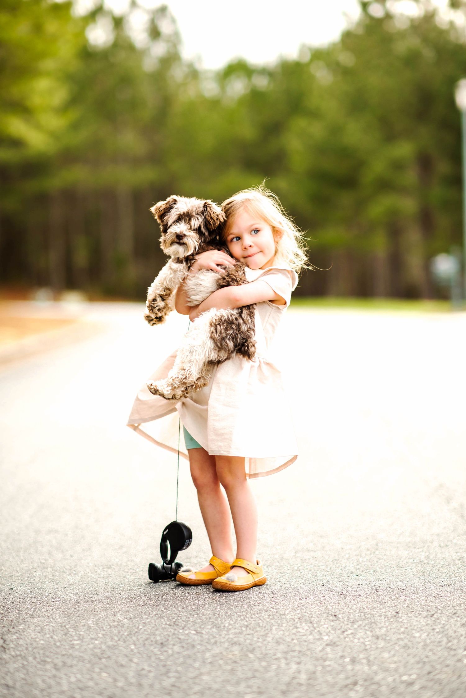 a little girl holding a dog in the road