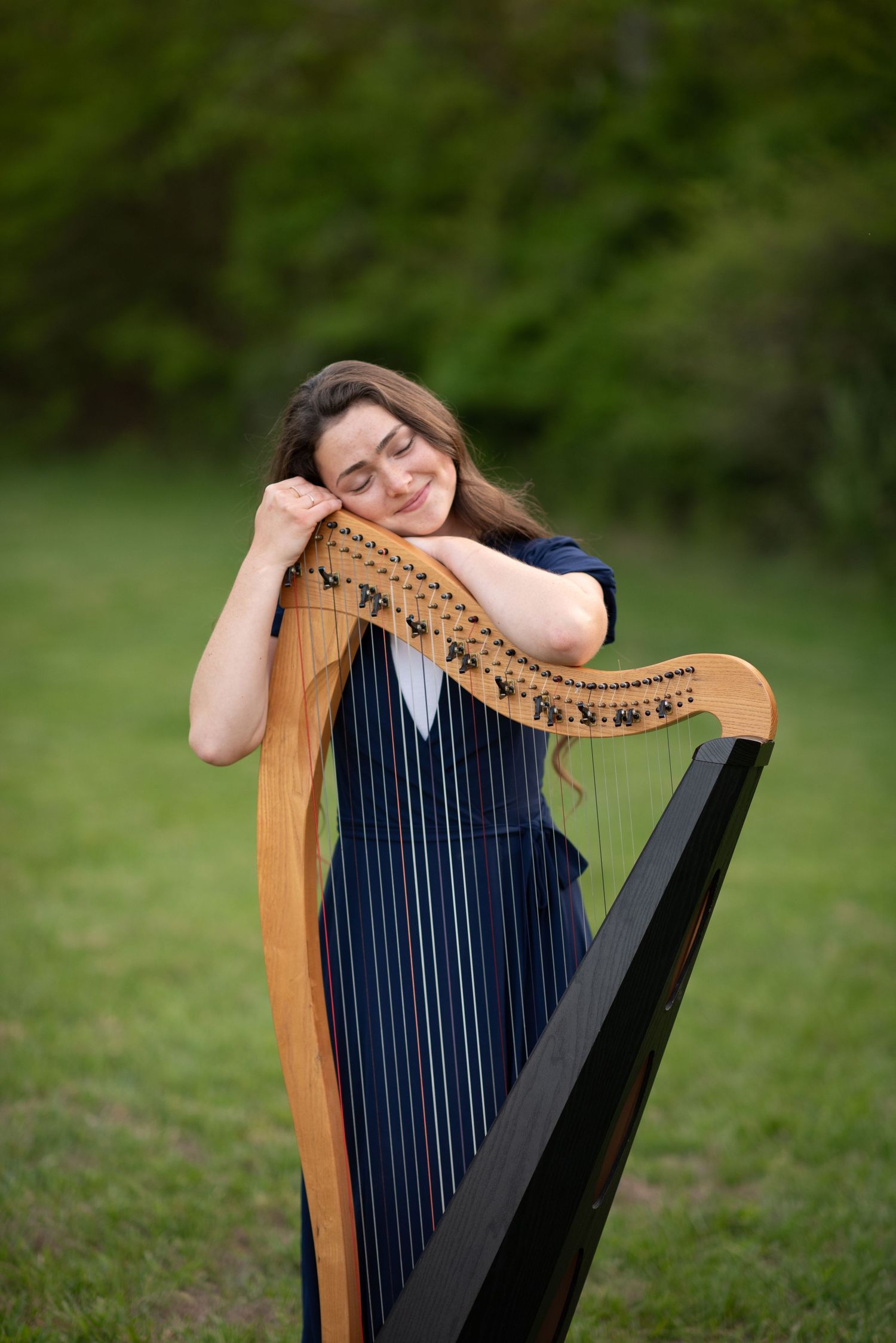 a girl leaning on a harp closing her eyes and smiling