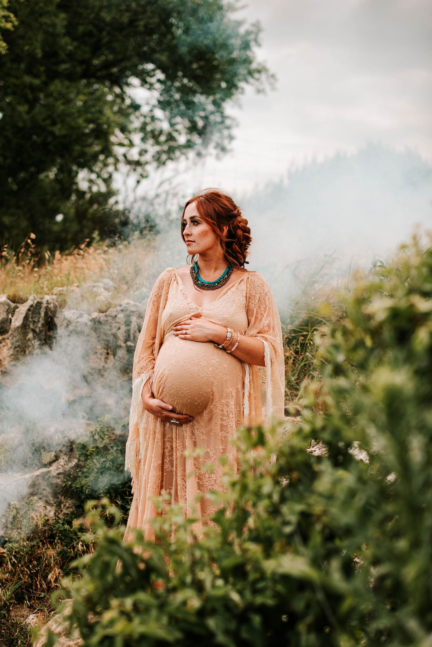 a pregnant mother holding her belly with smoke behind her