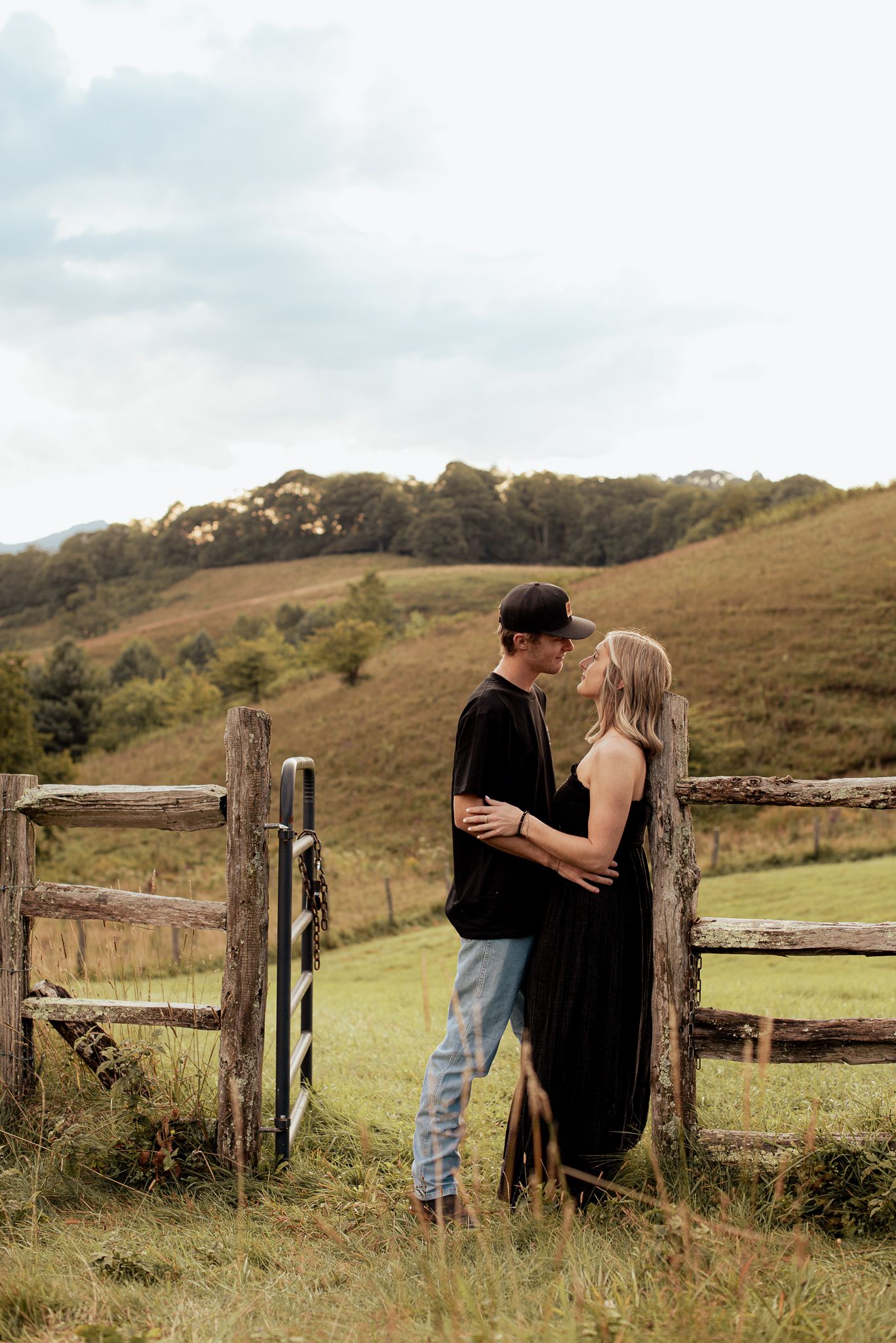 a couple in the countryside leaning on a fence and gazing lovingly