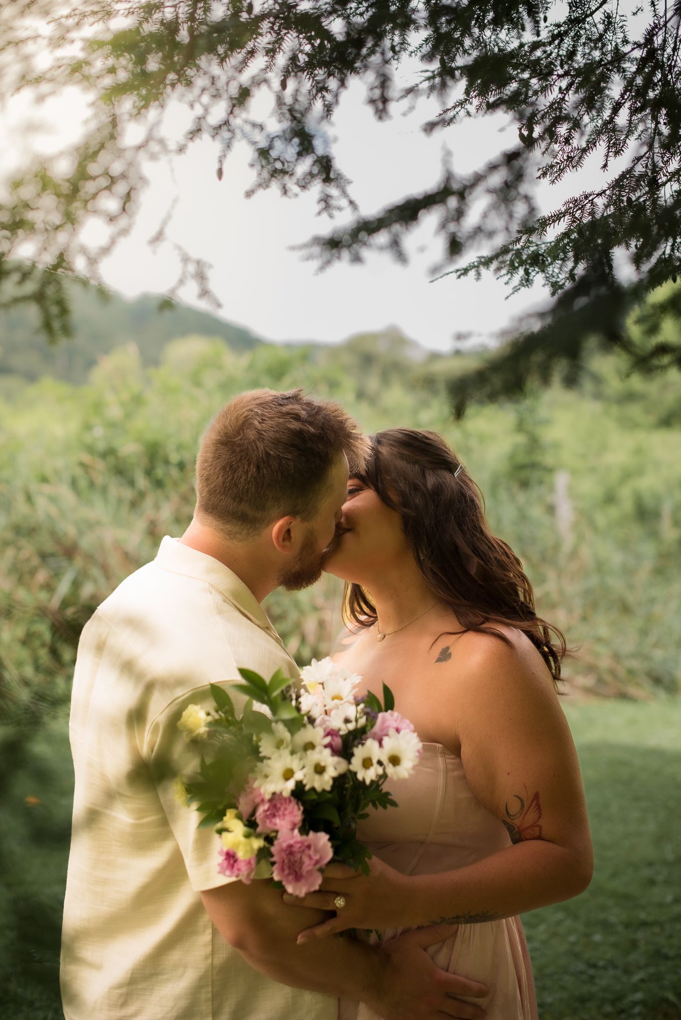 a couple kissing holding a bouquet of flowers