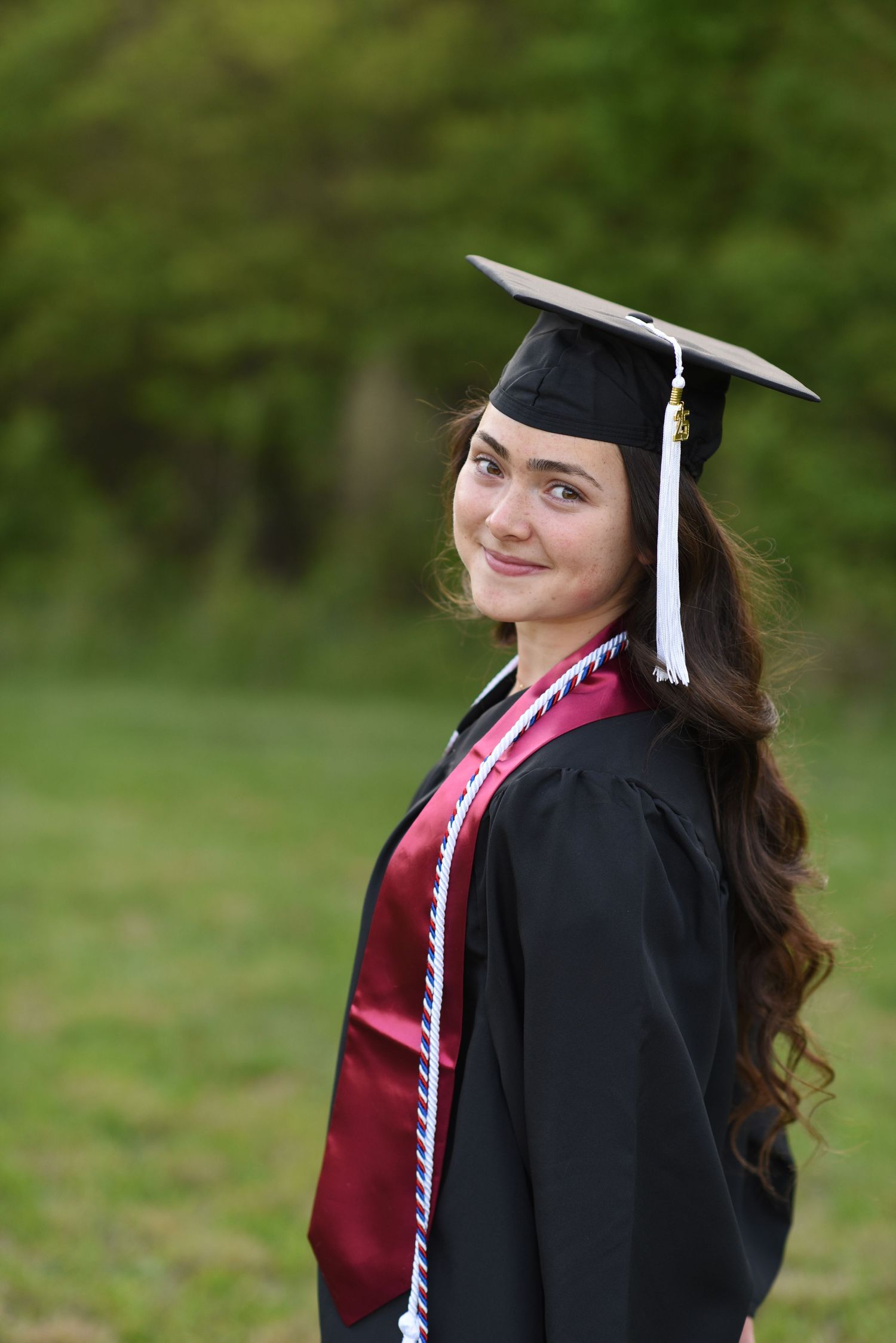 a girl in a cap and gown looking over her shoulder