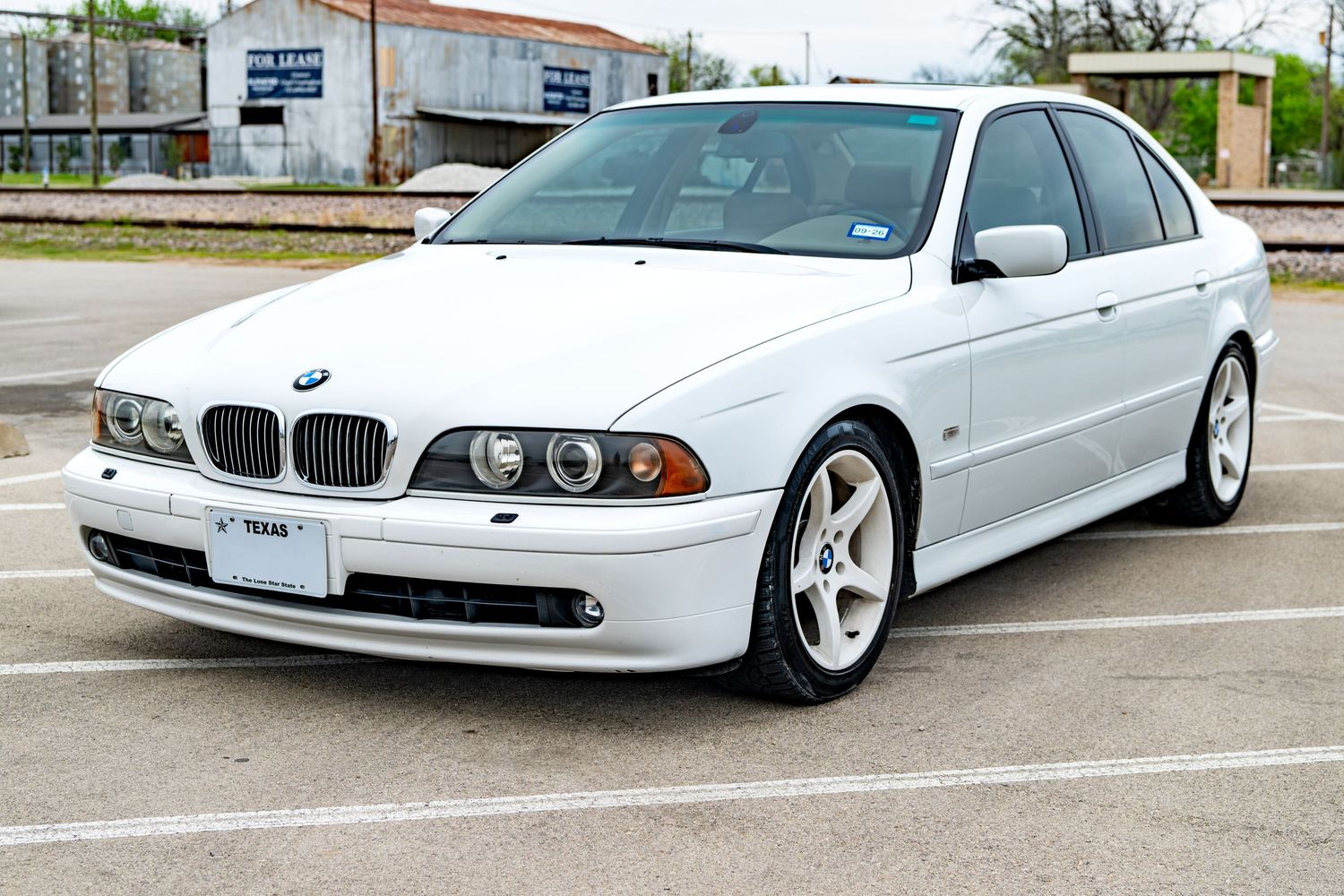 White BMW 5 Series E39 sedan parked in a lot, featuring classic styling, alloy wheels, and Texas license plate.