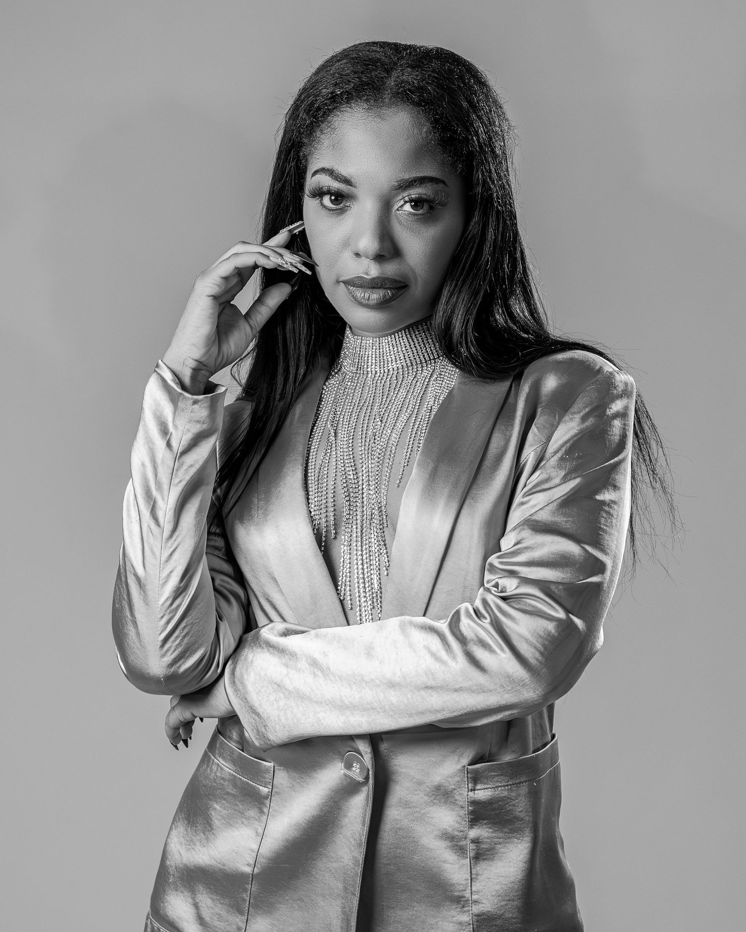 Black and white photo series showing a person in a shiny metallic jacket posing against a light background.
