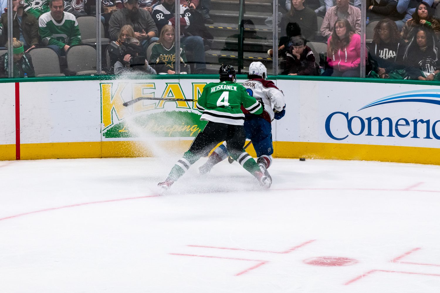 Hockey player in green jersey skates on ice during professional game.