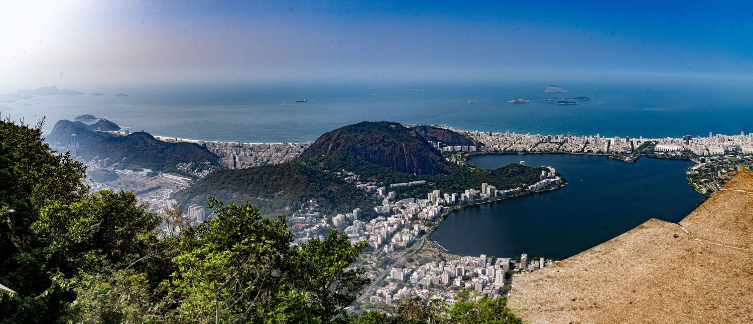 Panoramic coastal cityscape view with mountains and ocean under blue skies.