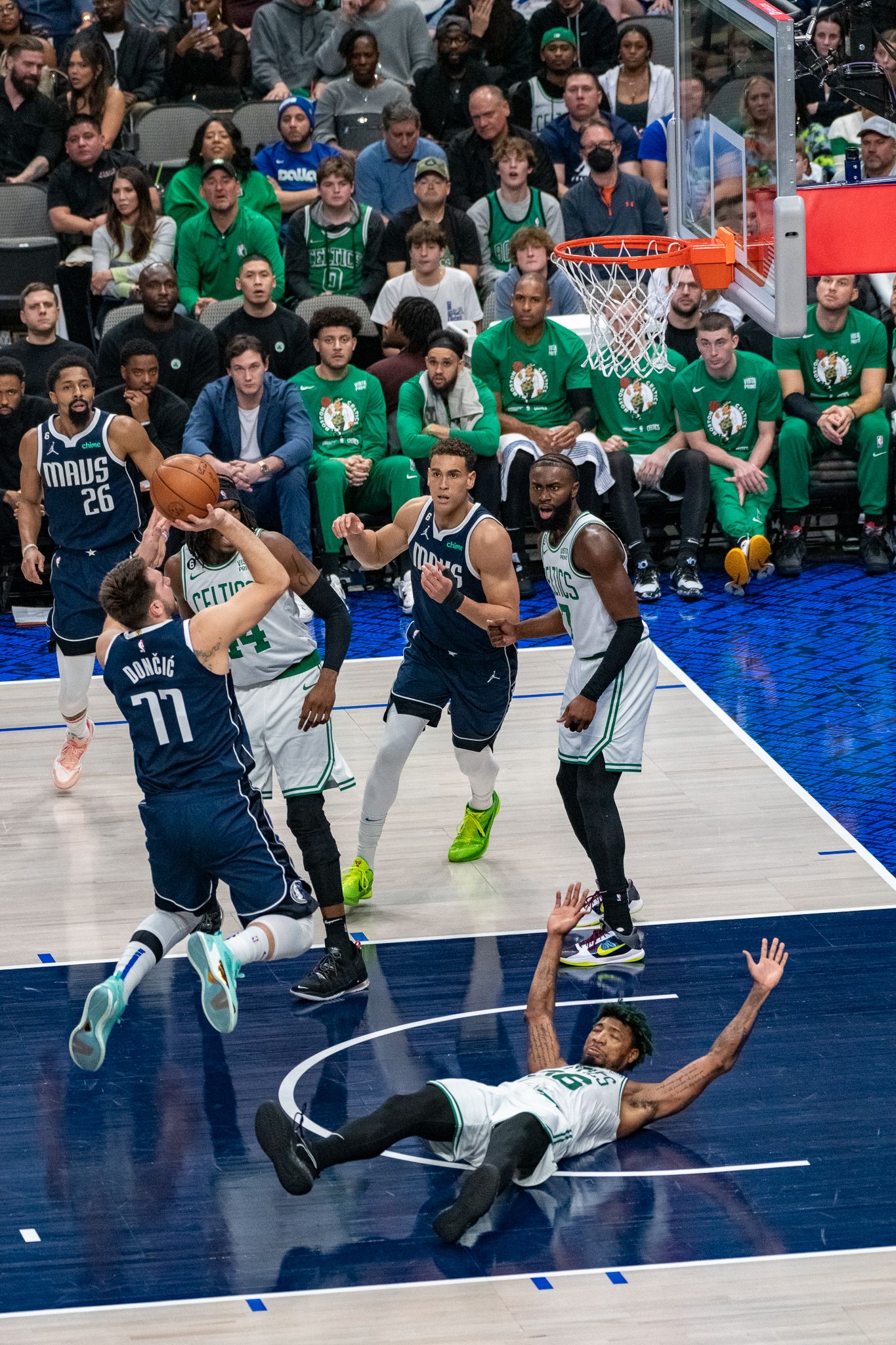 NBA basketball game action shot showing players from Celtics and Mavericks competing for the ball.