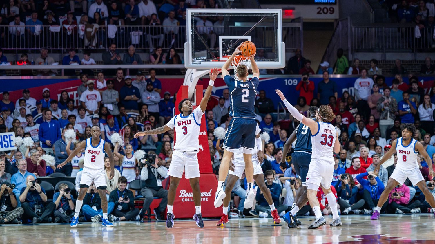 Basketball players compete on a professional court with a large crowd watching in the arena.