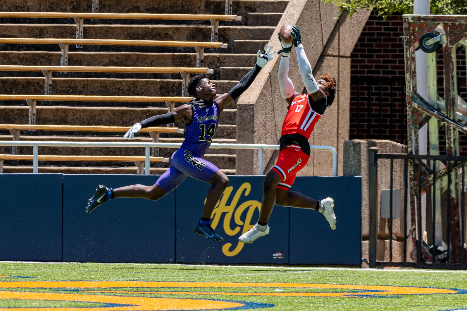 Athletes run and jump on an outdoor track field during a competitive event.