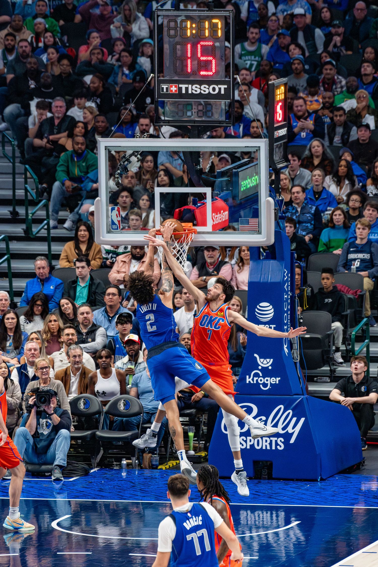 Basketball action shot showing players jumping for the ball near the hoop during a professional game.