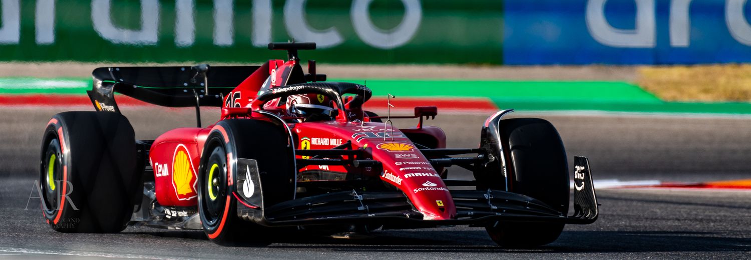 Racing car with Aramco livery competes on a Formula 1 circuit with green and red track markings.