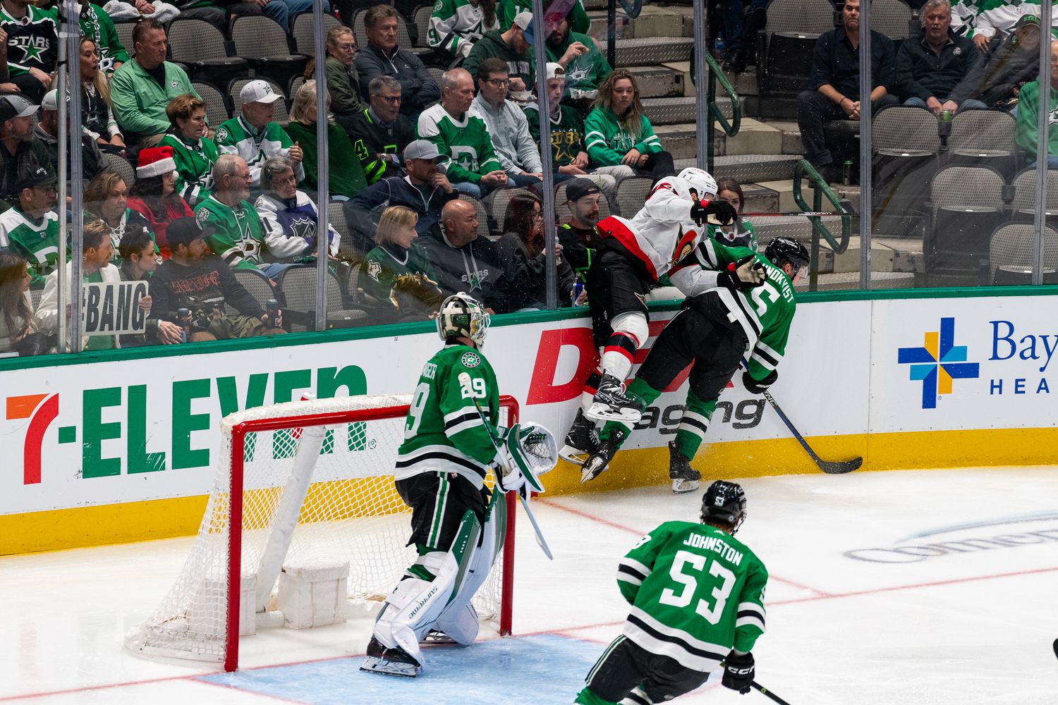 Hockey players from opposing teams battle for puck control near the goal.