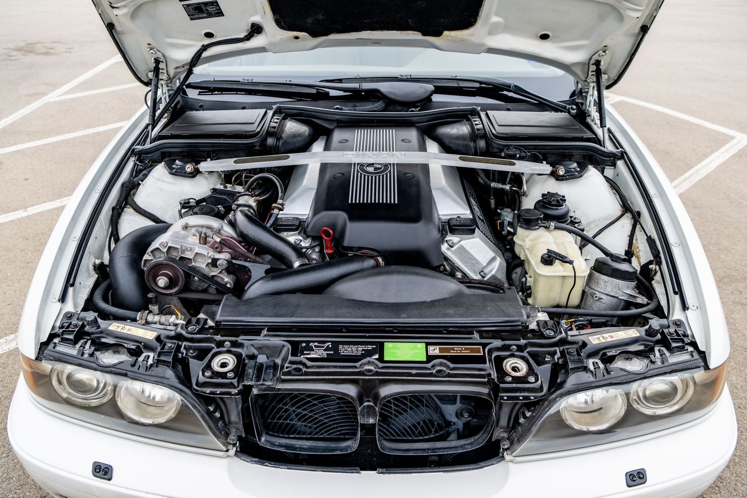 White BMW E46 with open hood revealing a clean high-performance engine bay with supercharger upgrade.