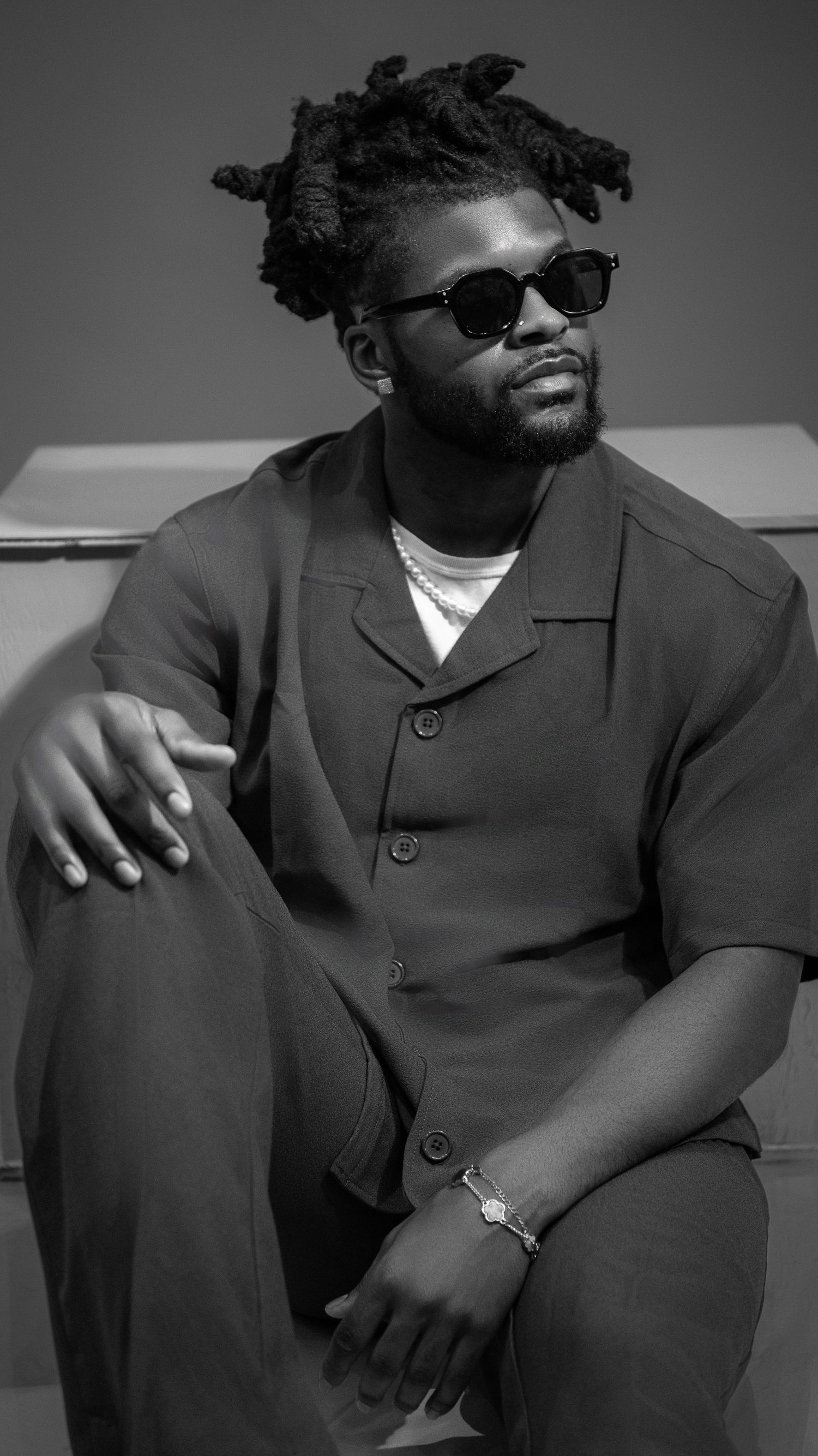 Black and white portrait series showing a figure in sunglasses and dark coat against light background.