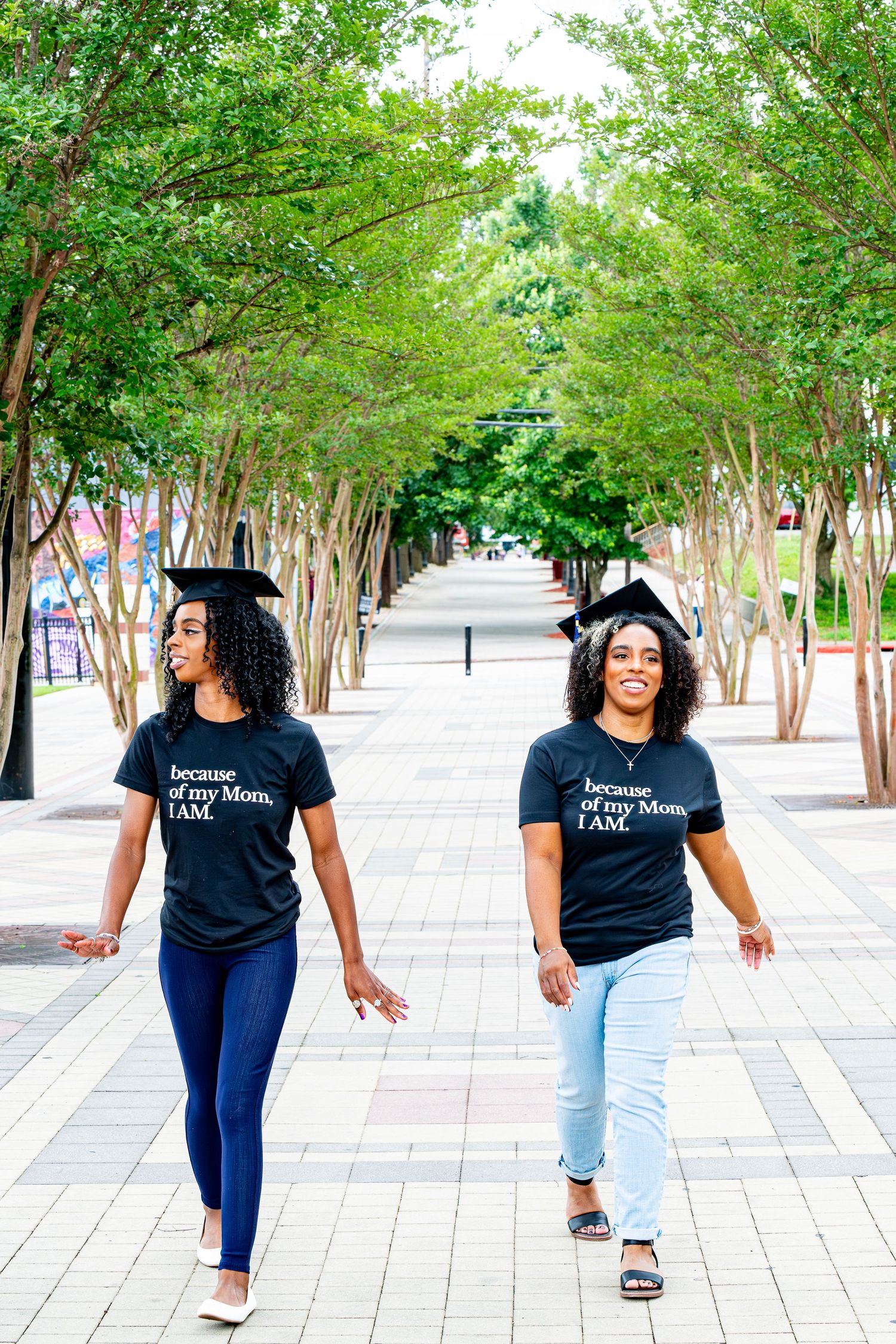Casual walking sequence on urban sidewalk wearing black t-shirt and jeans among green trees.