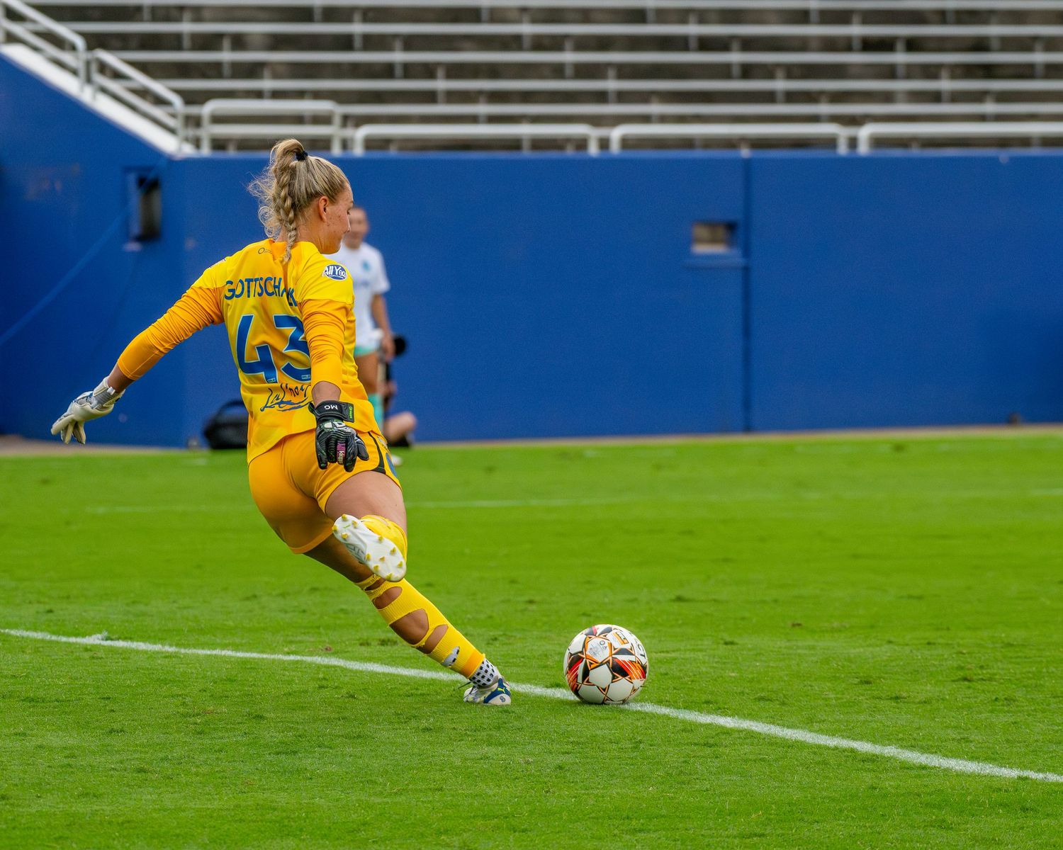 Goalkeeper in yellow uniform prepares to make a save during a soccer match.