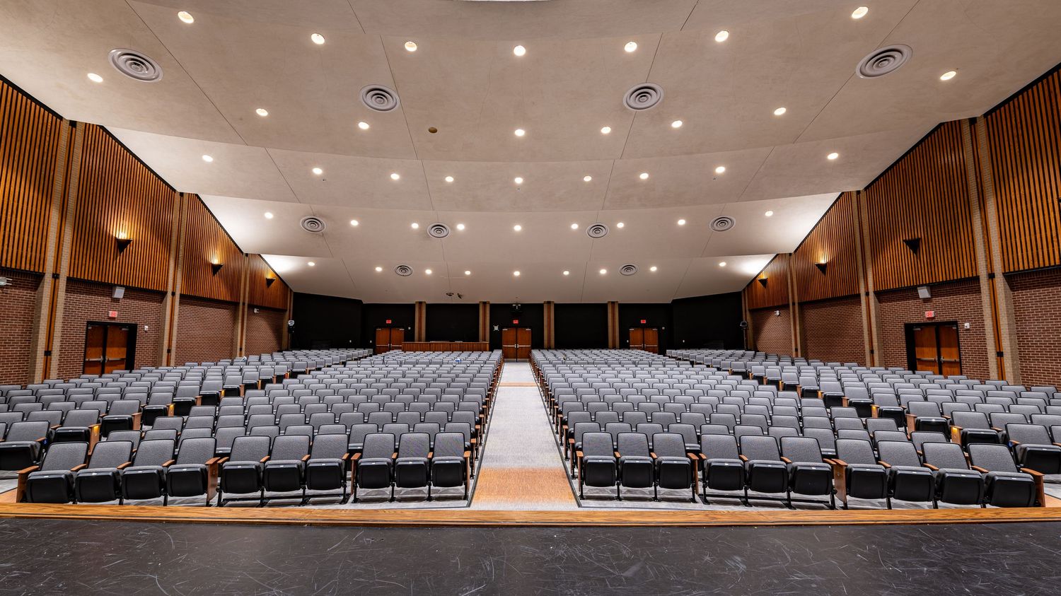 Long panoramic shot of an auditorium with wooden accents and theater seating.
