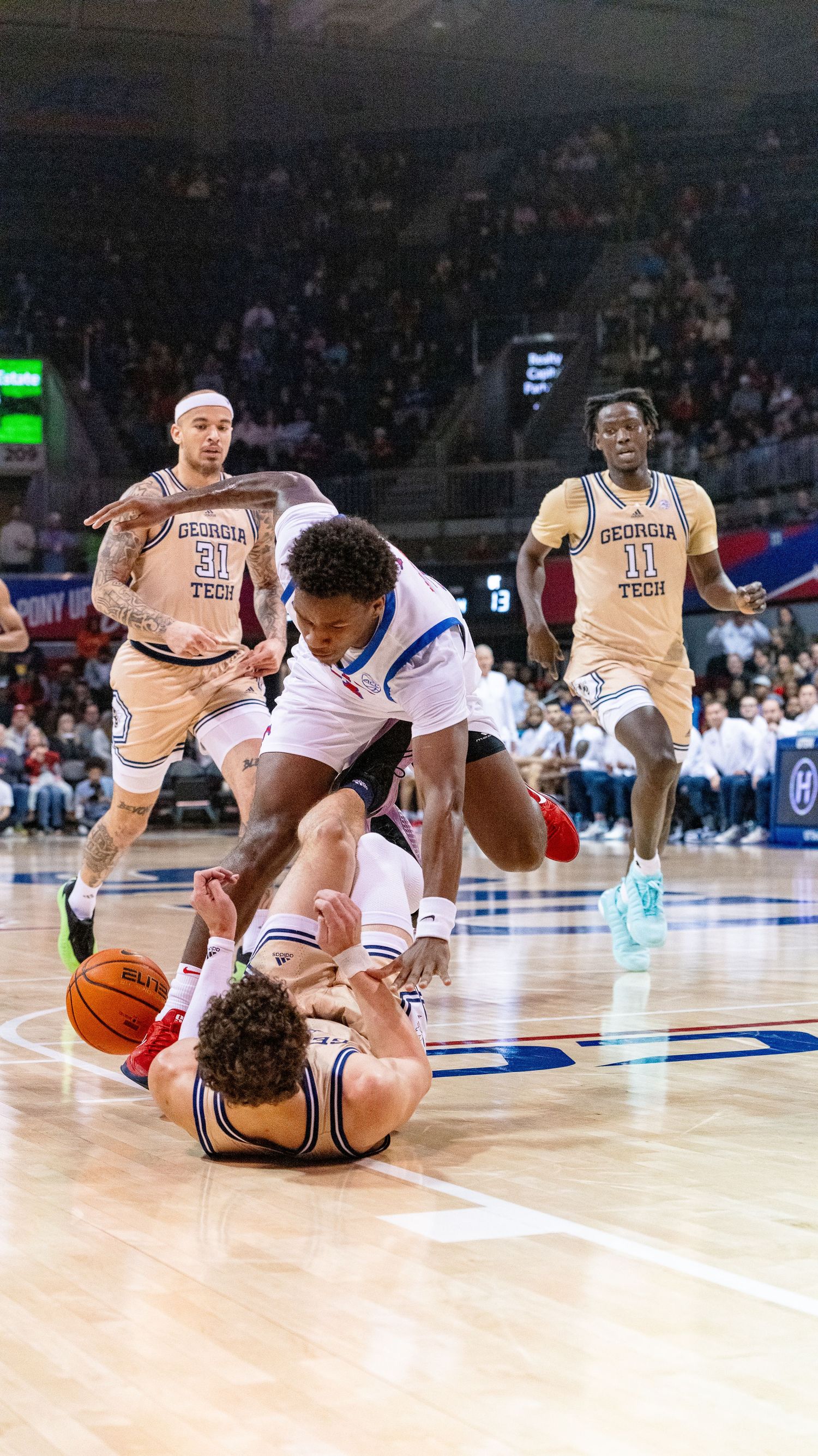 Basketball players dive for a loose ball during an intense moment on the court.