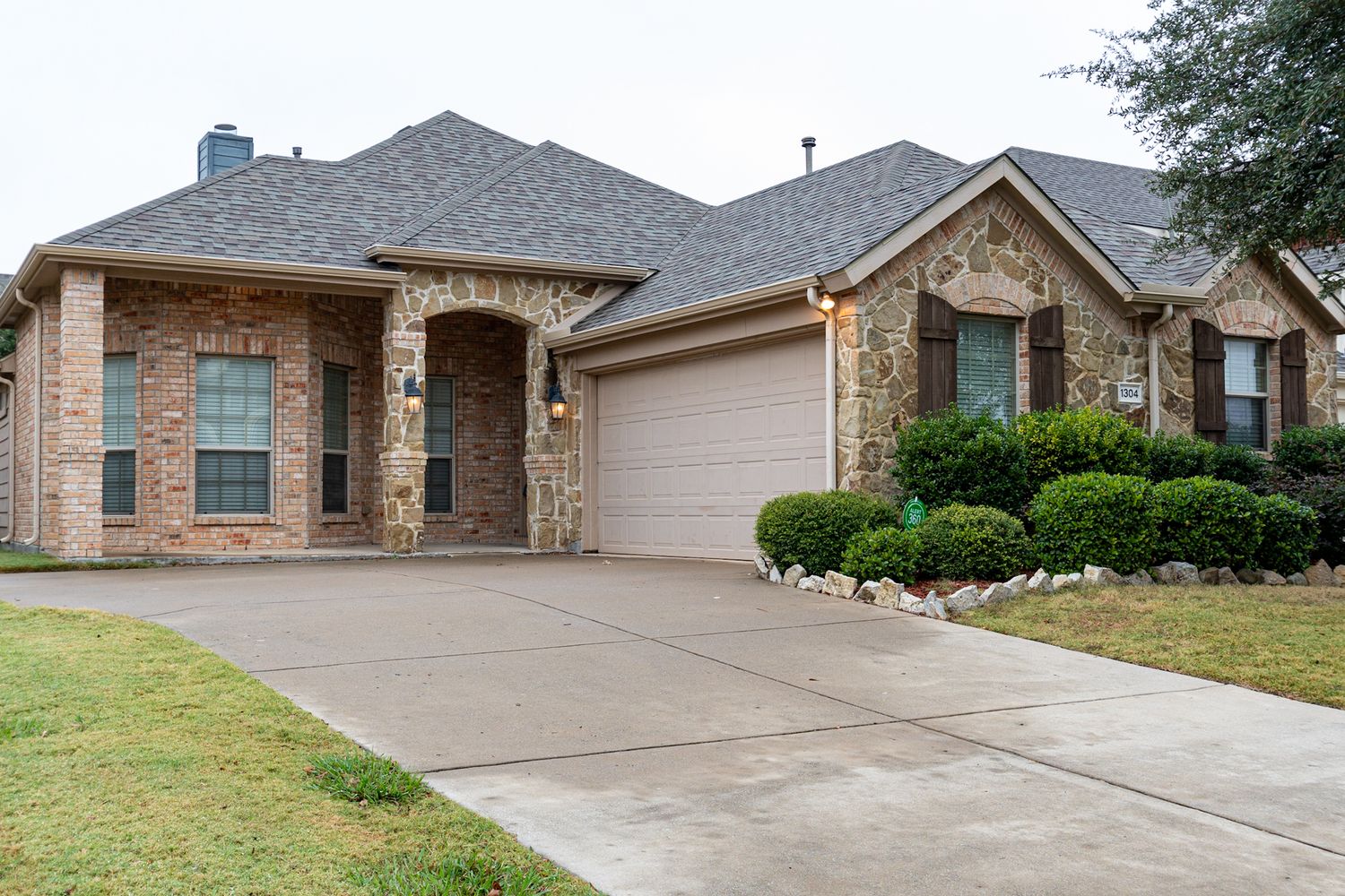 Modern suburban homes with stone facades and paved driveways on a residential street.