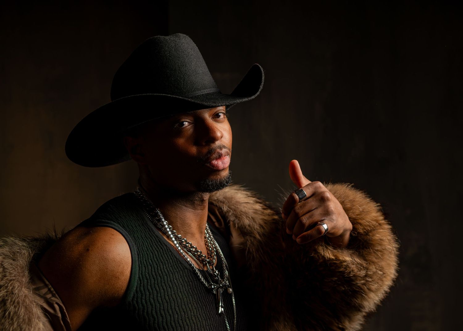 Dramatic fashion portrait series in dark lighting with fur coat and black hat against shadowy background.