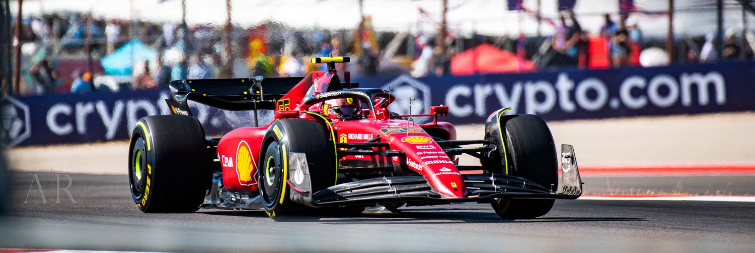 Red Formula 1 race car speeds past crypto.com advertising boards on a racing circuit.