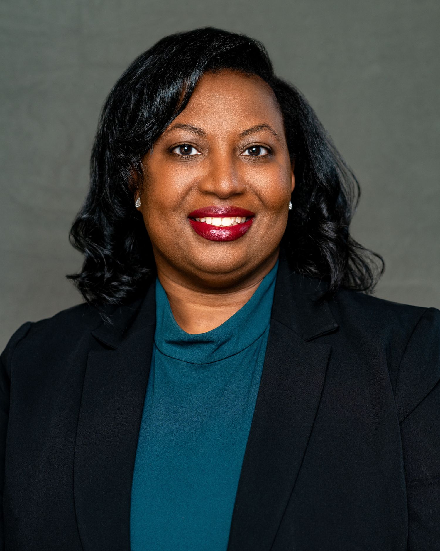 Professional headshots showing someone in a black blazer and teal turtleneck against a gray background.