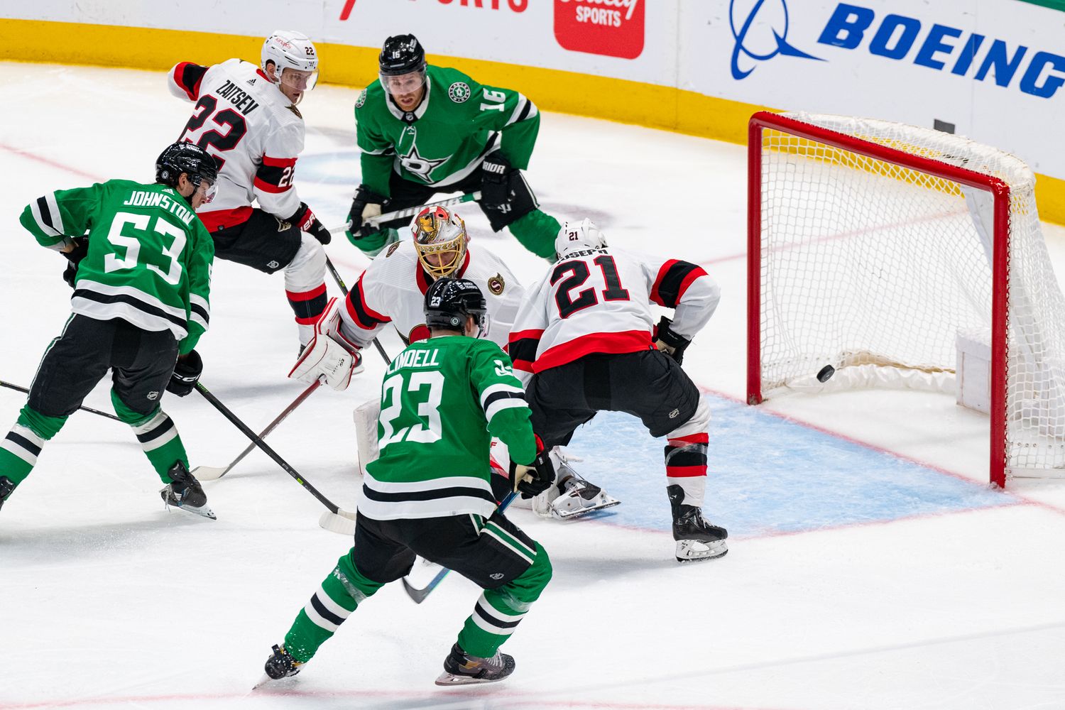 NHL players scramble for position during intense goal-mouth action.