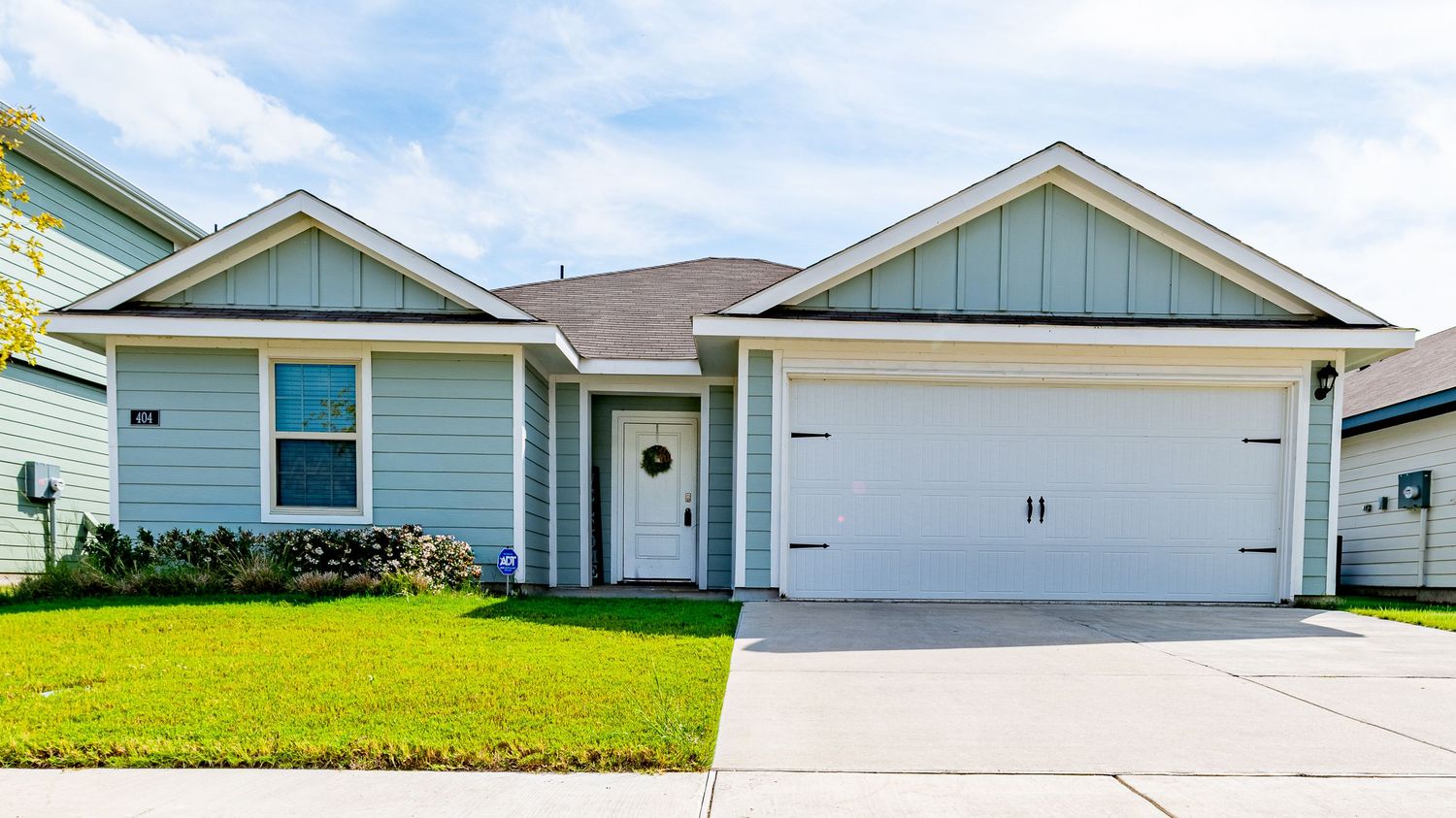 Row of modern suburban homes with garages and well-maintained lawns.