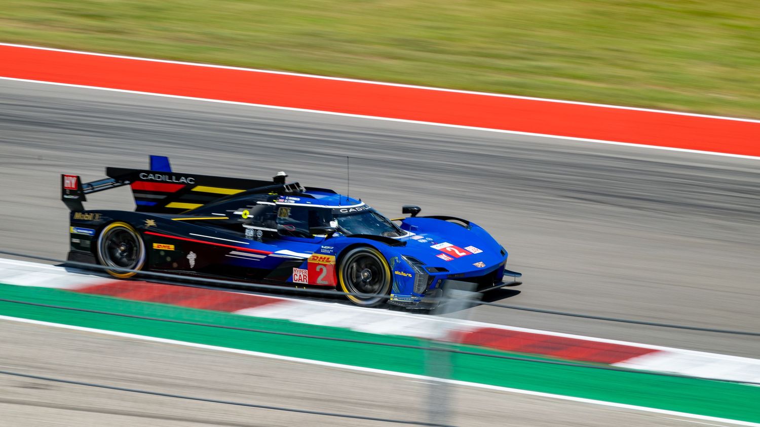 Race cars speed around a track during a motorsport competition.