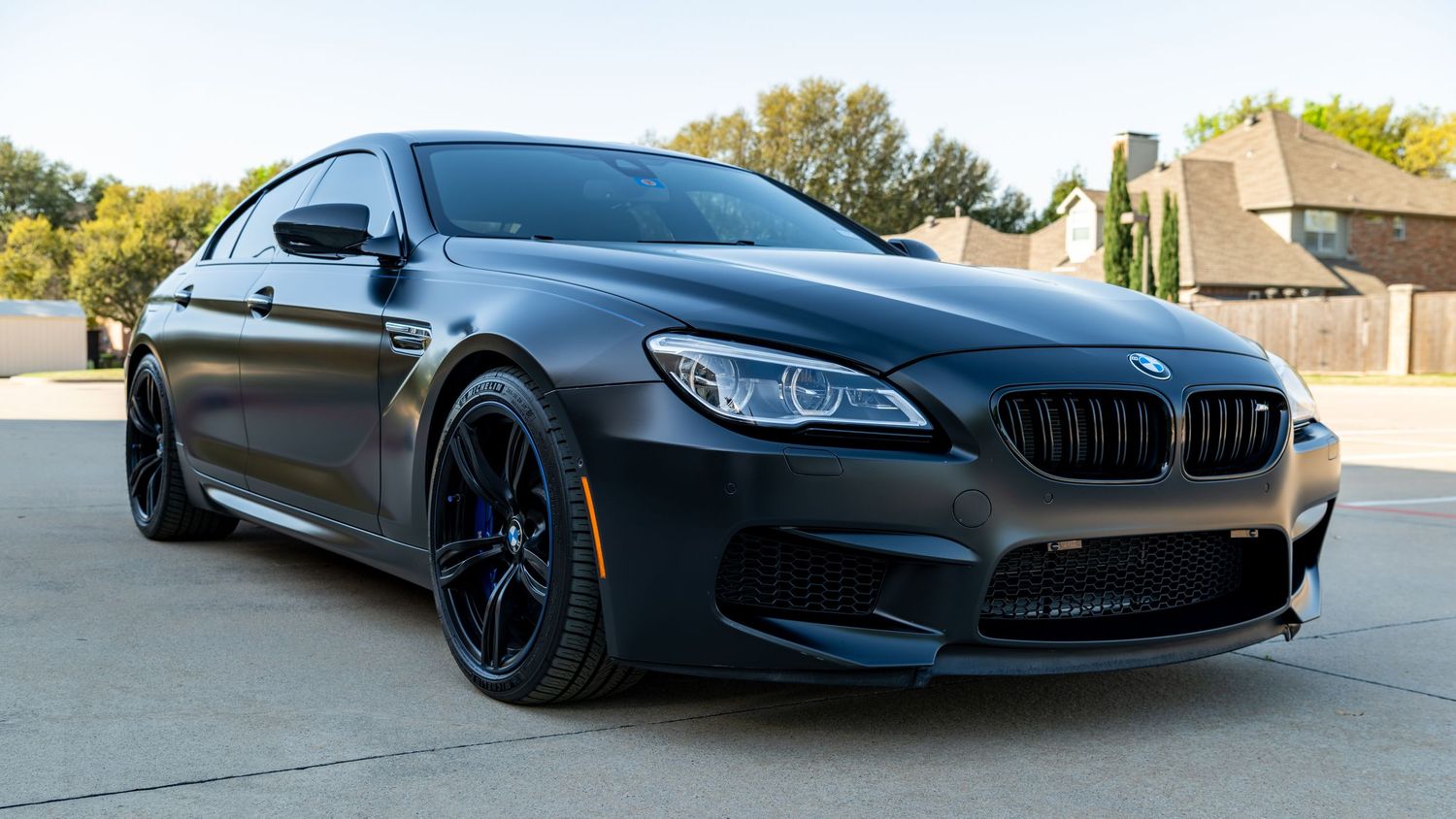 Matte black BMW M6 coupe parked outdoors, featuring aggressive M Sport styling, black alloy wheels, and sleek fastback roofline.