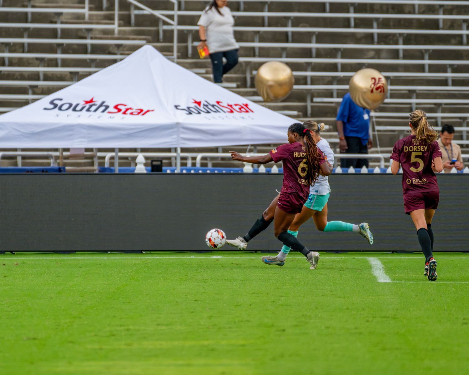 Wide angle view of a soccer match with players competing on a sunny day at the stadium.
