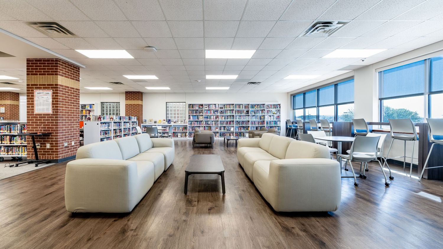 Panoramic view of a modern library interior with bookshelves and large windows.