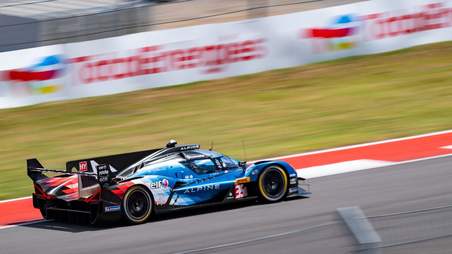 Racing cars blur past on a professional circuit during a high-speed competition.