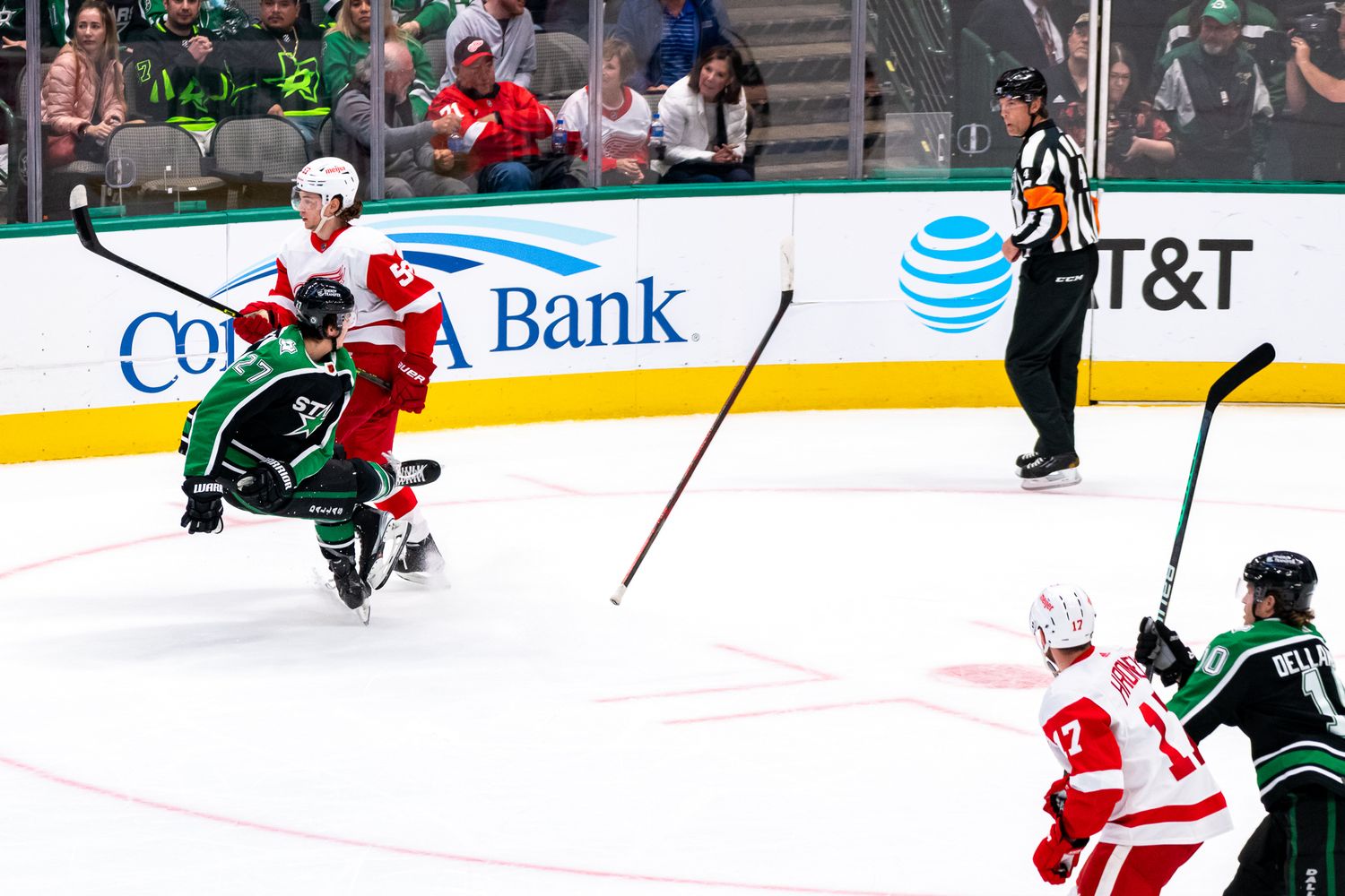 Hockey players from opposing teams in red and green jerseys battle for the puck during an intense game.