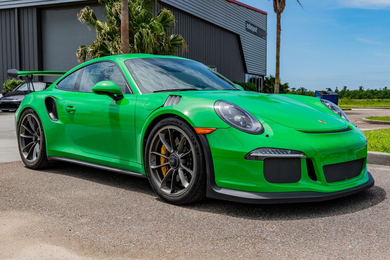 Vibrant green Porsche 911 GT3 RS sports car parked outdoors, featuring black wheels with yellow brake calipers.