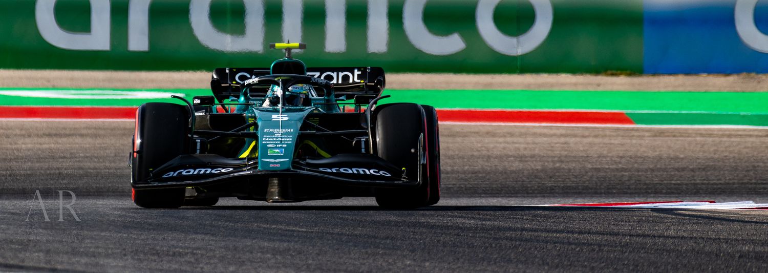 F1 car with Aramco sponsorship navigates a turn on a racing track.