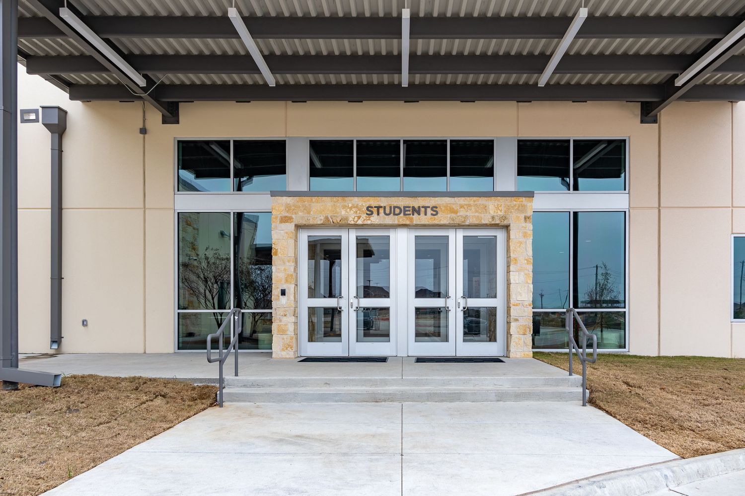 Modern commercial building exterior with covered walkway and metal awning structure extending along the facade.