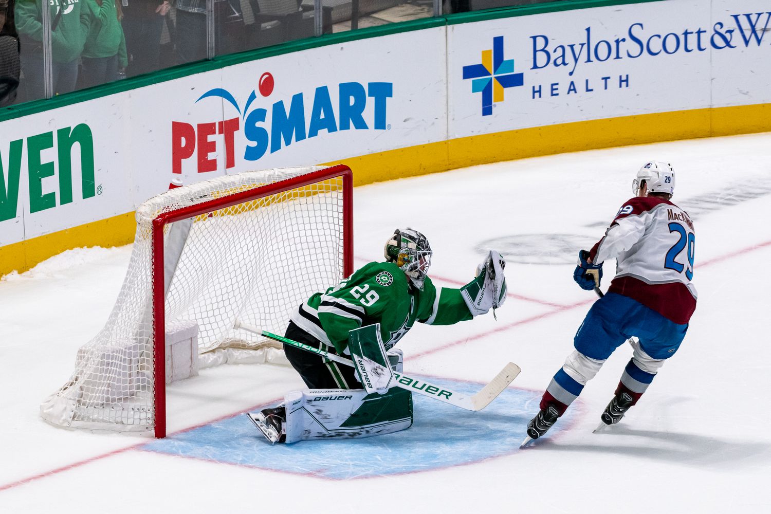 Hockey player attempts to score against goalie during NHL game with PetSmart advertisement visible.
