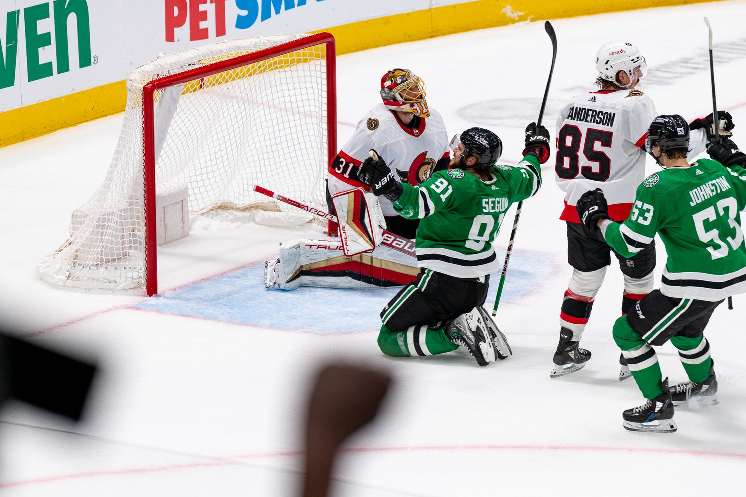 NHL hockey players compete near the goal with PetSmart advertising boards visible in background.