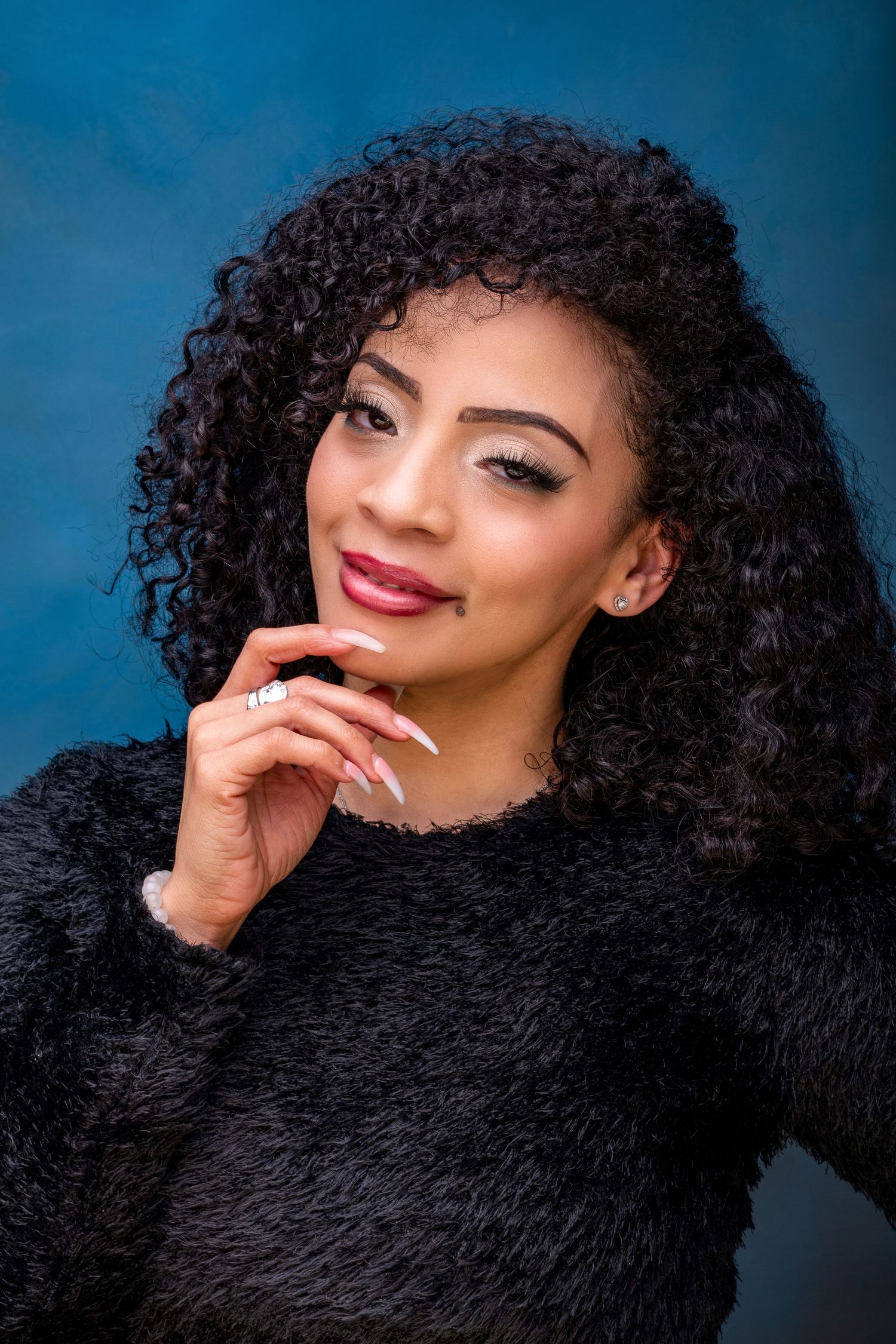 Beauty portraits against blue background featuring curly hair and red lipstick.