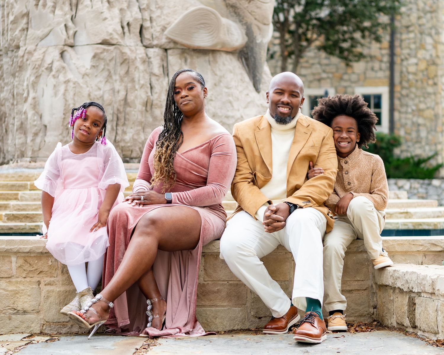 Group sitting together on stone steps in coordinated pink and beige outfits.