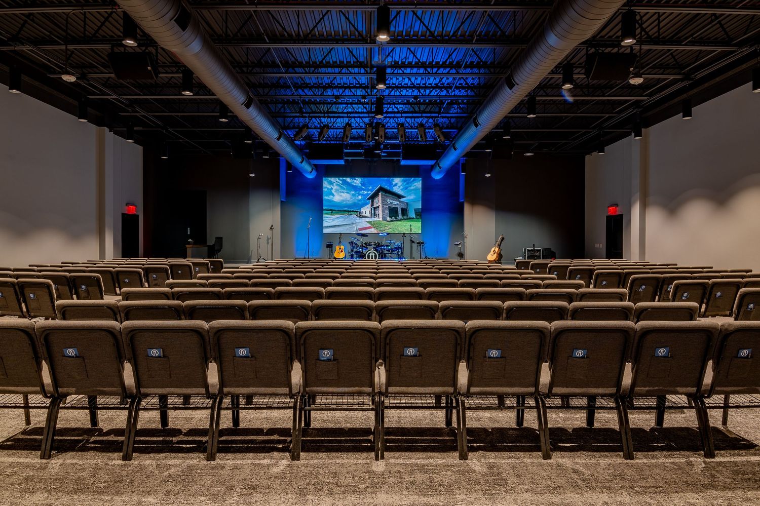 Large empty auditorium with rows of seats and blue lighting on the ceiling.