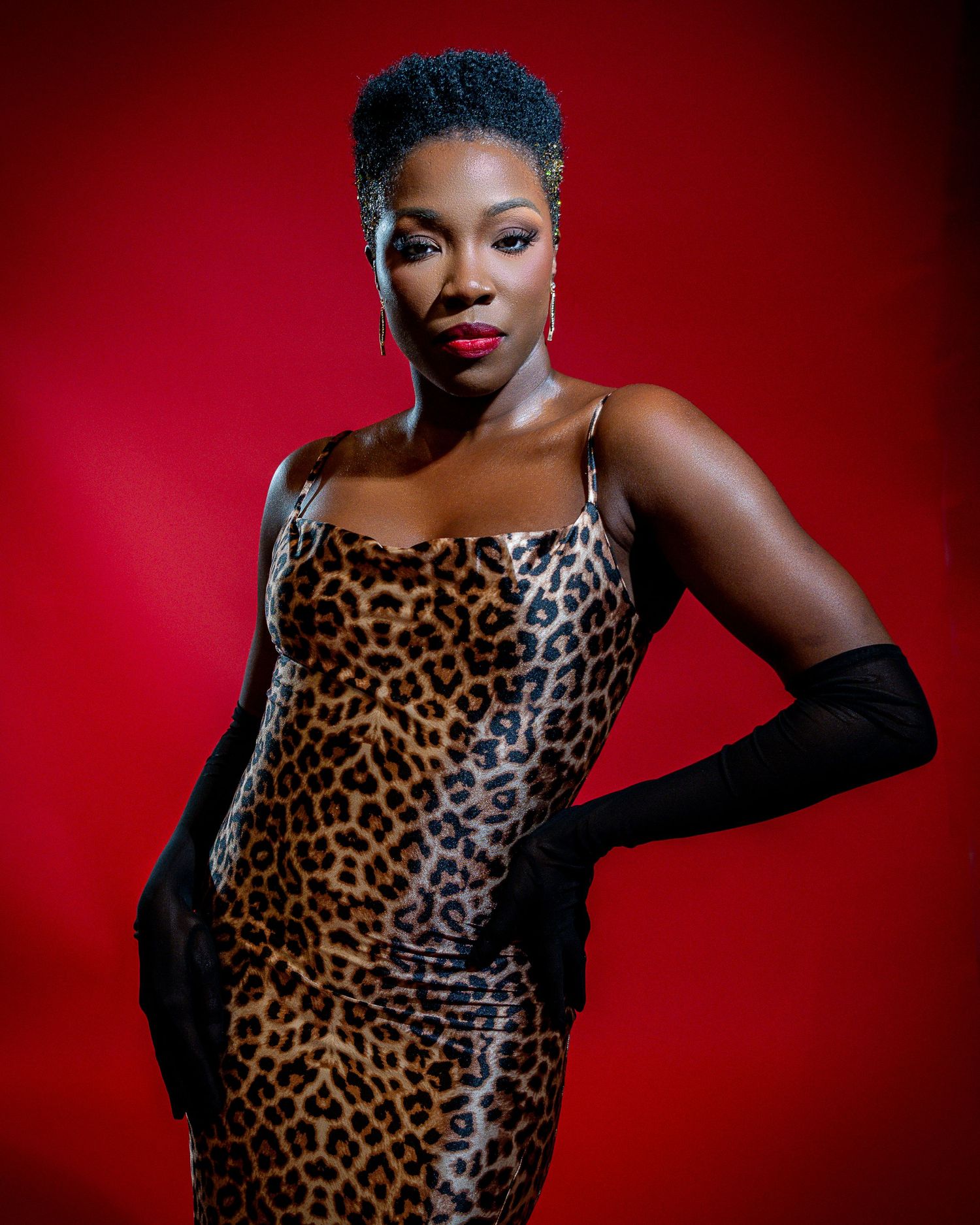 Dramatic fashion poses in leopard print top against deep red background.