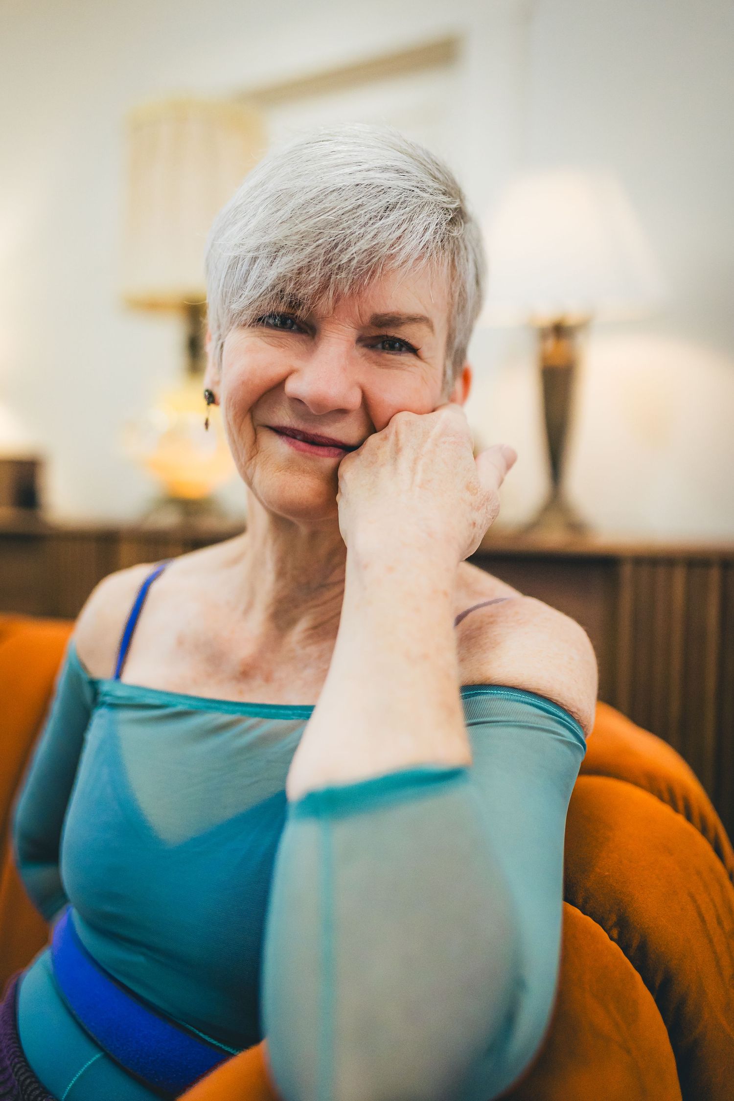 Older woman with short gray hair smiling warmly while resting her chin on her hand.